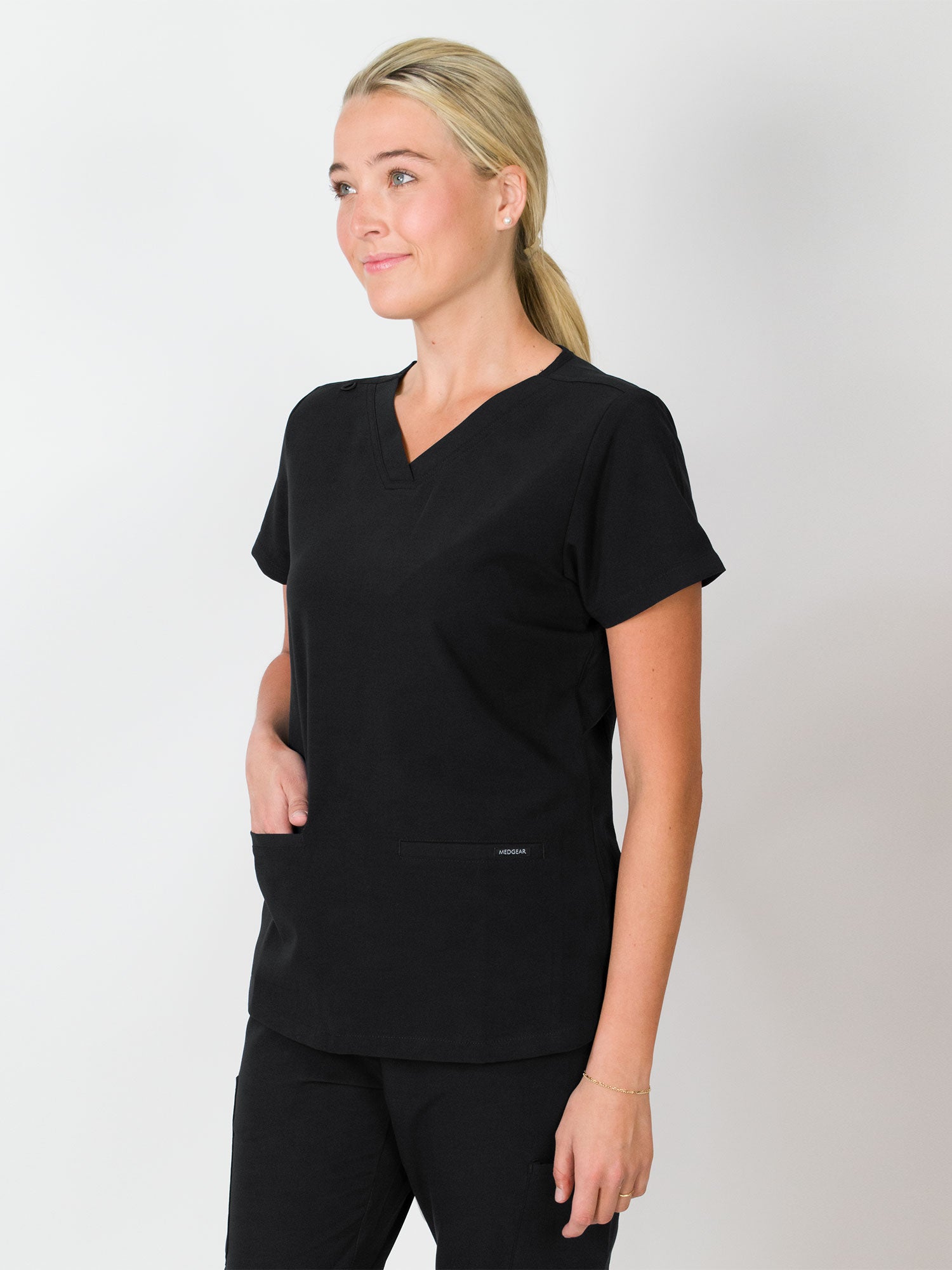 A woman wearing a gray, V-neck, three-pocket top with a slim fit, made from MG-LUX fabric.