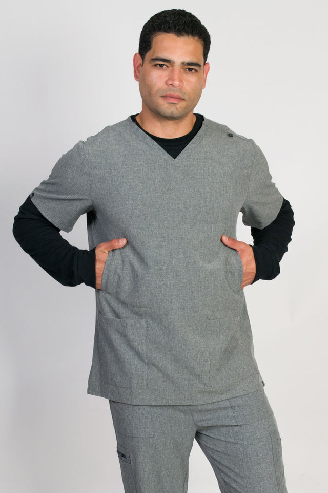 A male wearing a gray scrubs top with a classic V-neckline and 5 pockets, including handwarmers on the sides.