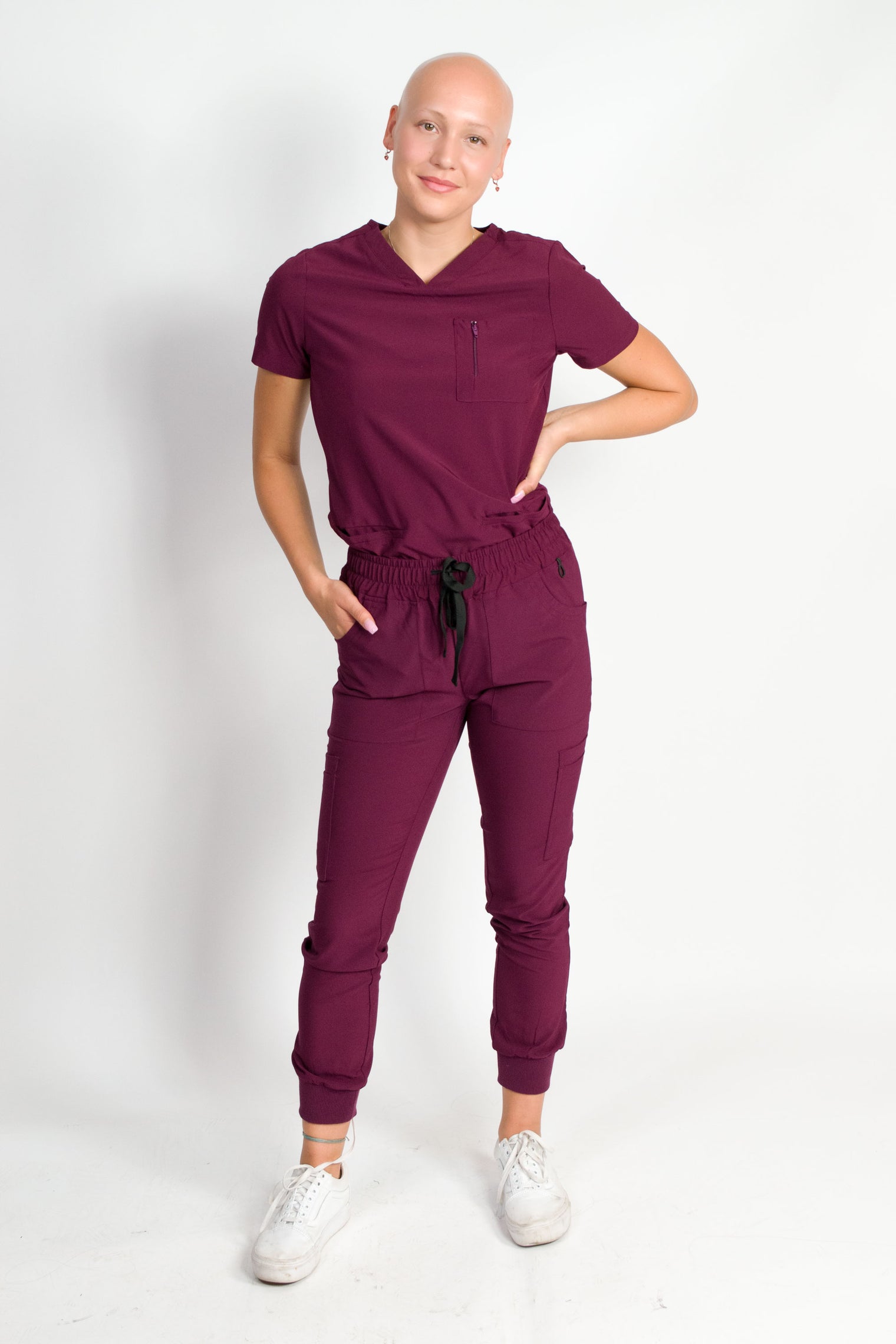 Scrub set in burgundy color with a mitered neck V-neck top and jogger pants, both with multiple pockets, made from a smooth stretch fabric.