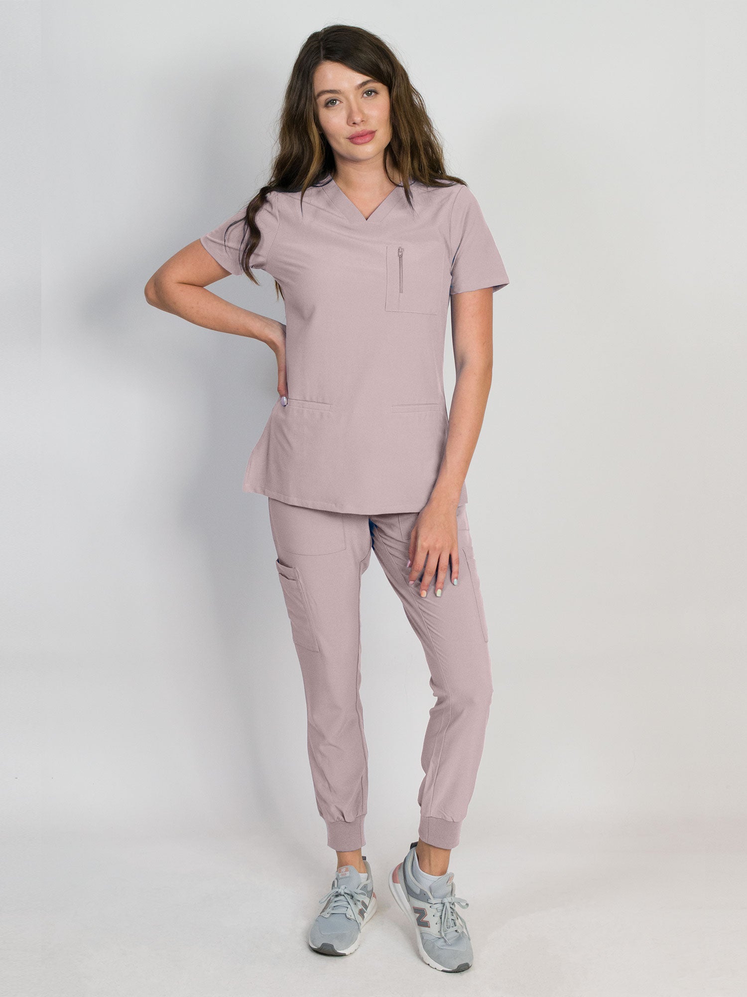 Orchid pink scrub set with a mitered neck V-neck top and jogger pants, both with multiple pockets, made from a smooth stretch fabric.