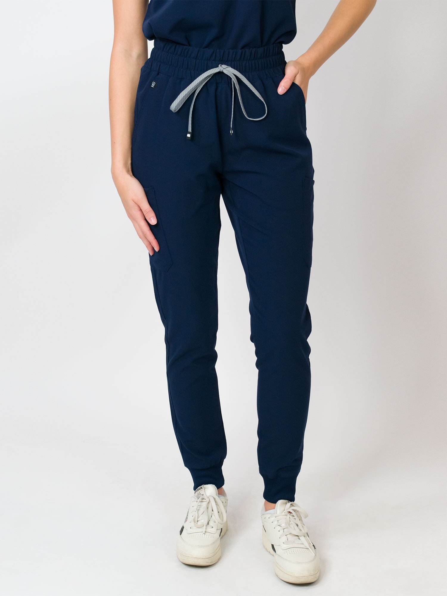 Navy color mid-rise slim jogger scrub pants with Medgear branding, an elastic waistband and drawstring, with multiple pockets.