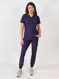 Woman modeling a purple medical scrub set with a V-neck top and jogger scrub pants