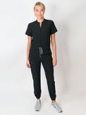 Black Medgear scrub jumpsuit with a mandarin collar, short sleeves, and elastic jogger cuffs. The jumpsuit has multiple pockets and a zipper front.