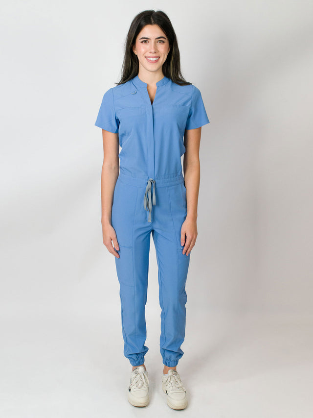Ceil blue scrub jumpsuit with a mandarin collar, short sleeves, and elastic jogger cuffs. The jumpsuit has multiple pockets and a zipper front.