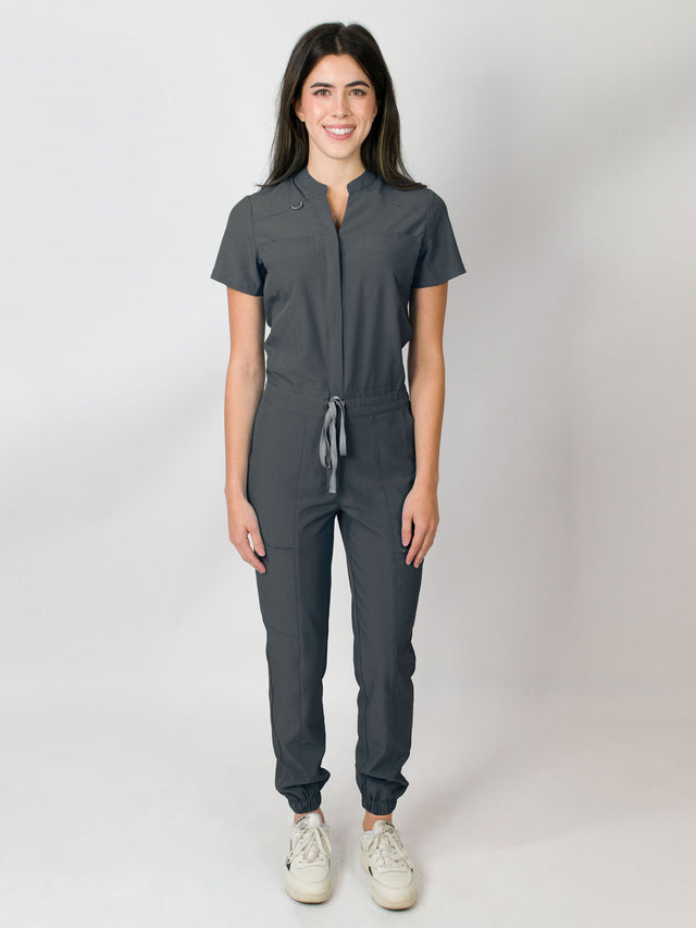 Grey scrub jumpsuit with a mandarin collar, short sleeves, and elastic jogger cuffs. The jumpsuit has multiple pockets and a zipper front.